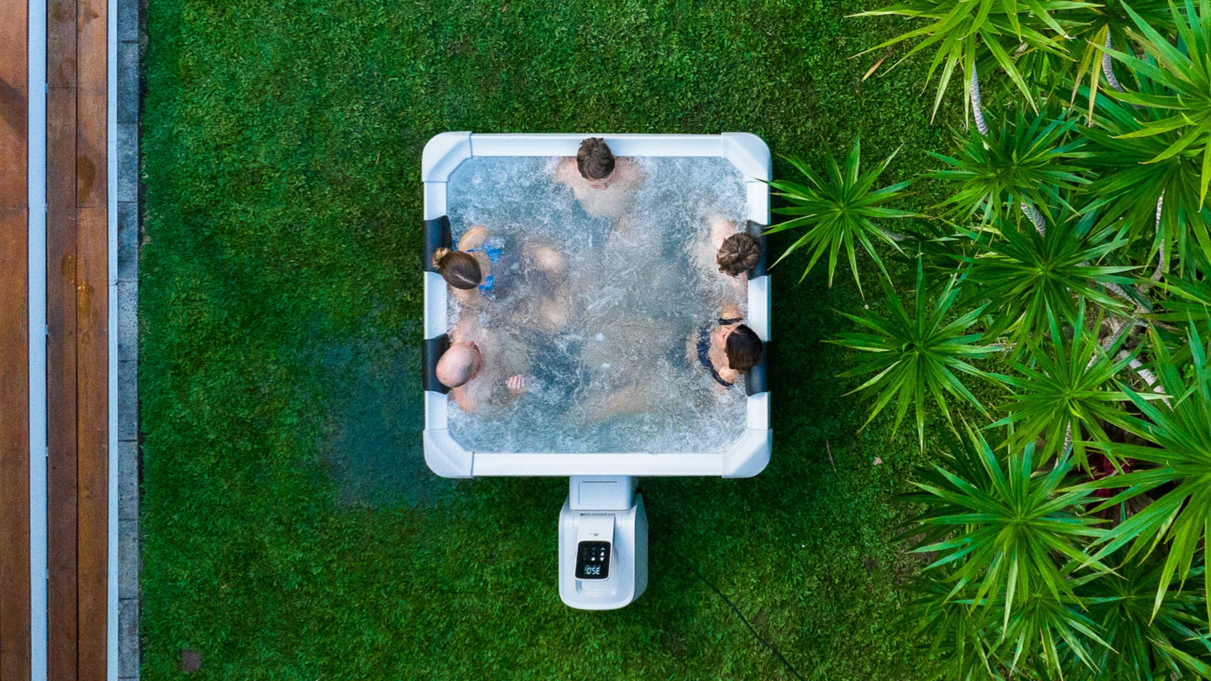 Top-down view of happy family relaxing in a square framed portable hot tub jacuzzi spa situated in a peaceful garden setting