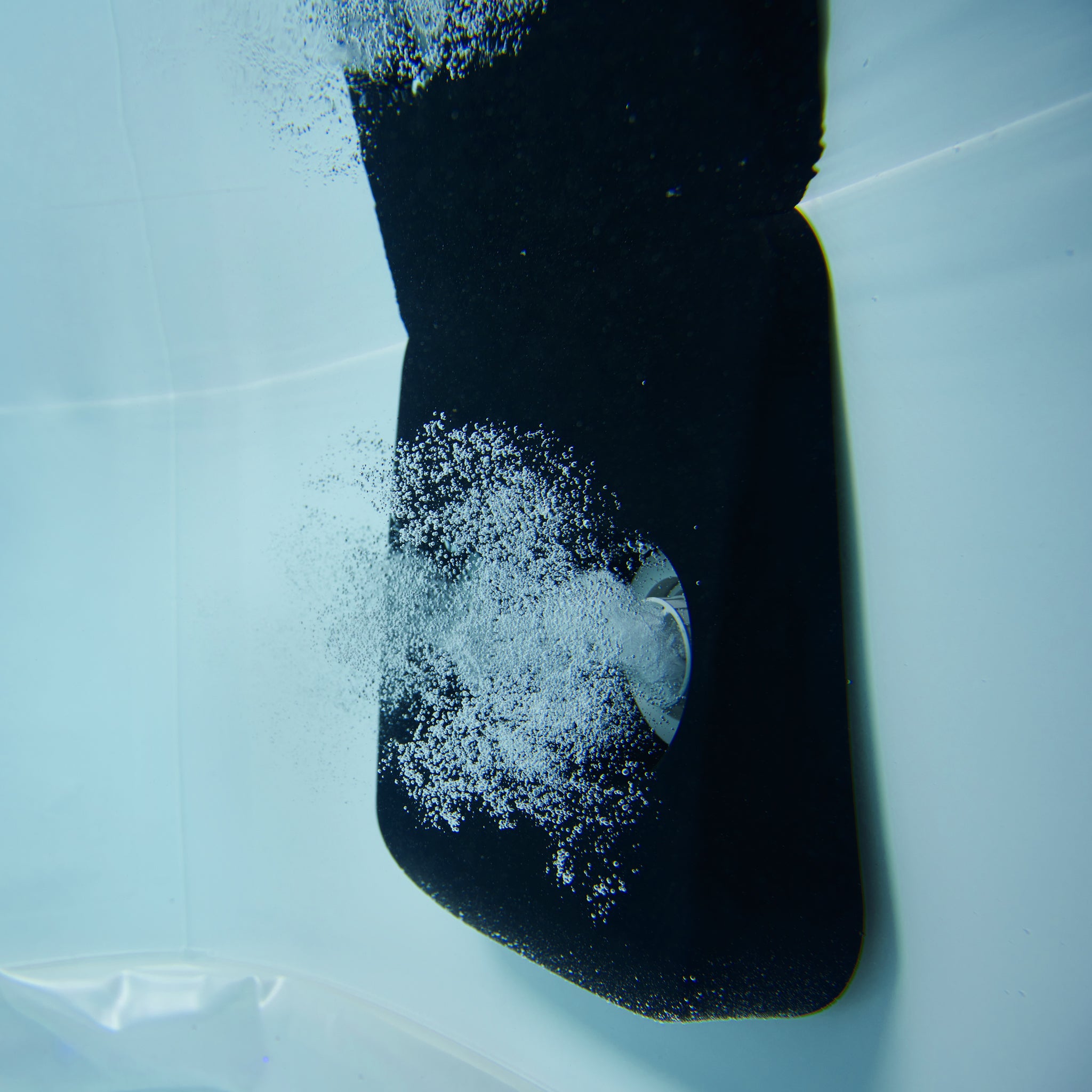 Underwater close up image of spa hydro jet blowing out a jet of bubbles into a portable hot tub jacuzzi.